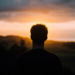 Mentally strong man standing confidently at sunrise symbolizing resilience, positivity, and personal growth.