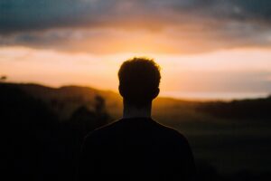 Mentally strong man standing confidently at sunrise symbolizing resilience, positivity, and personal growth.